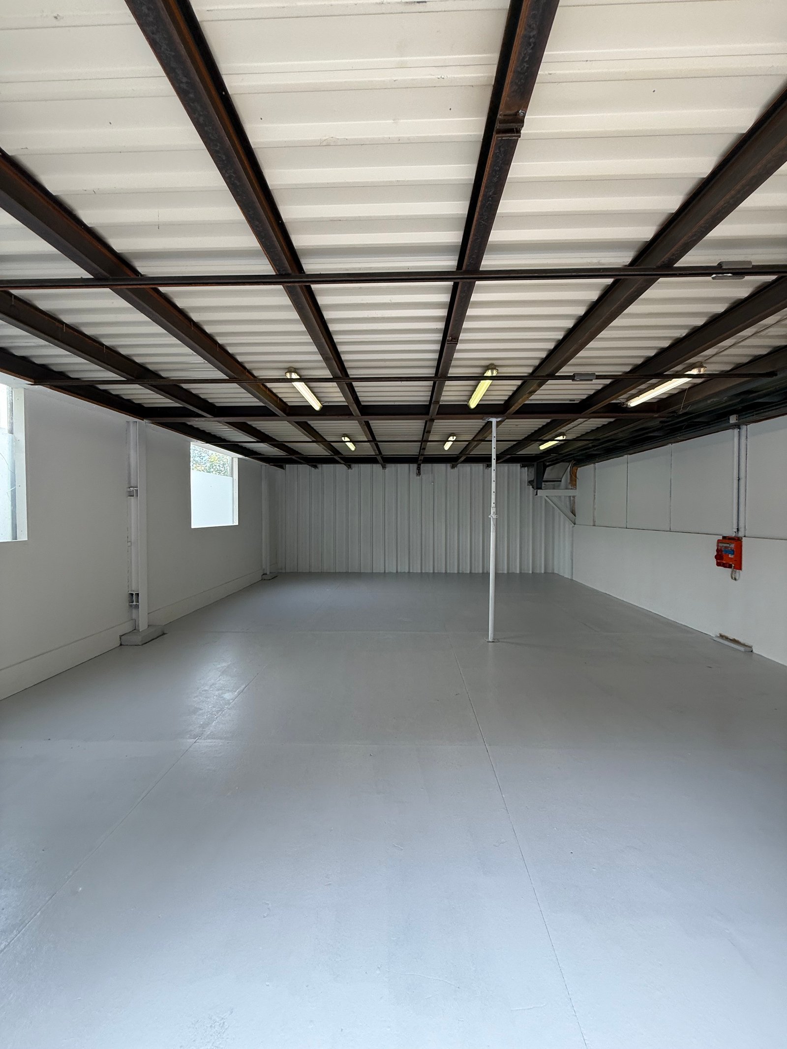Halle industrielle après intervention MNPro — sol en peinture 2K gris clair, murs giclés Epoxy blanc