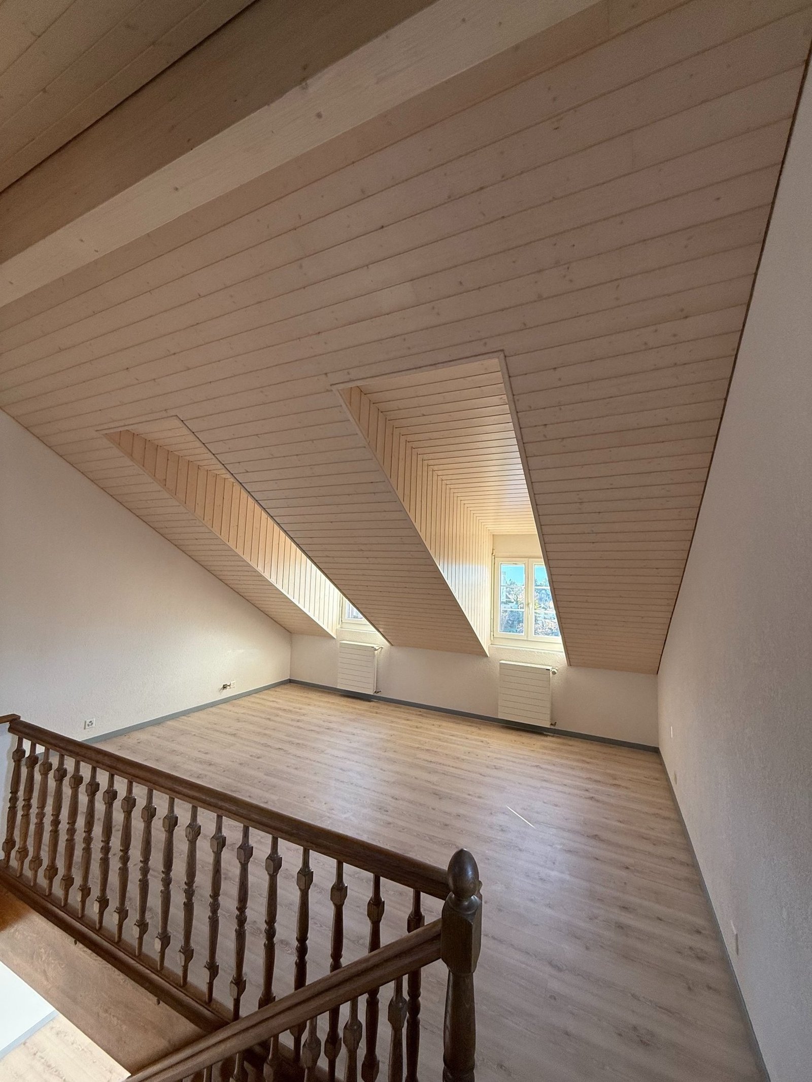Combles rénovés avec poutres et escalier bois traités — chantier MNPro en Valais
