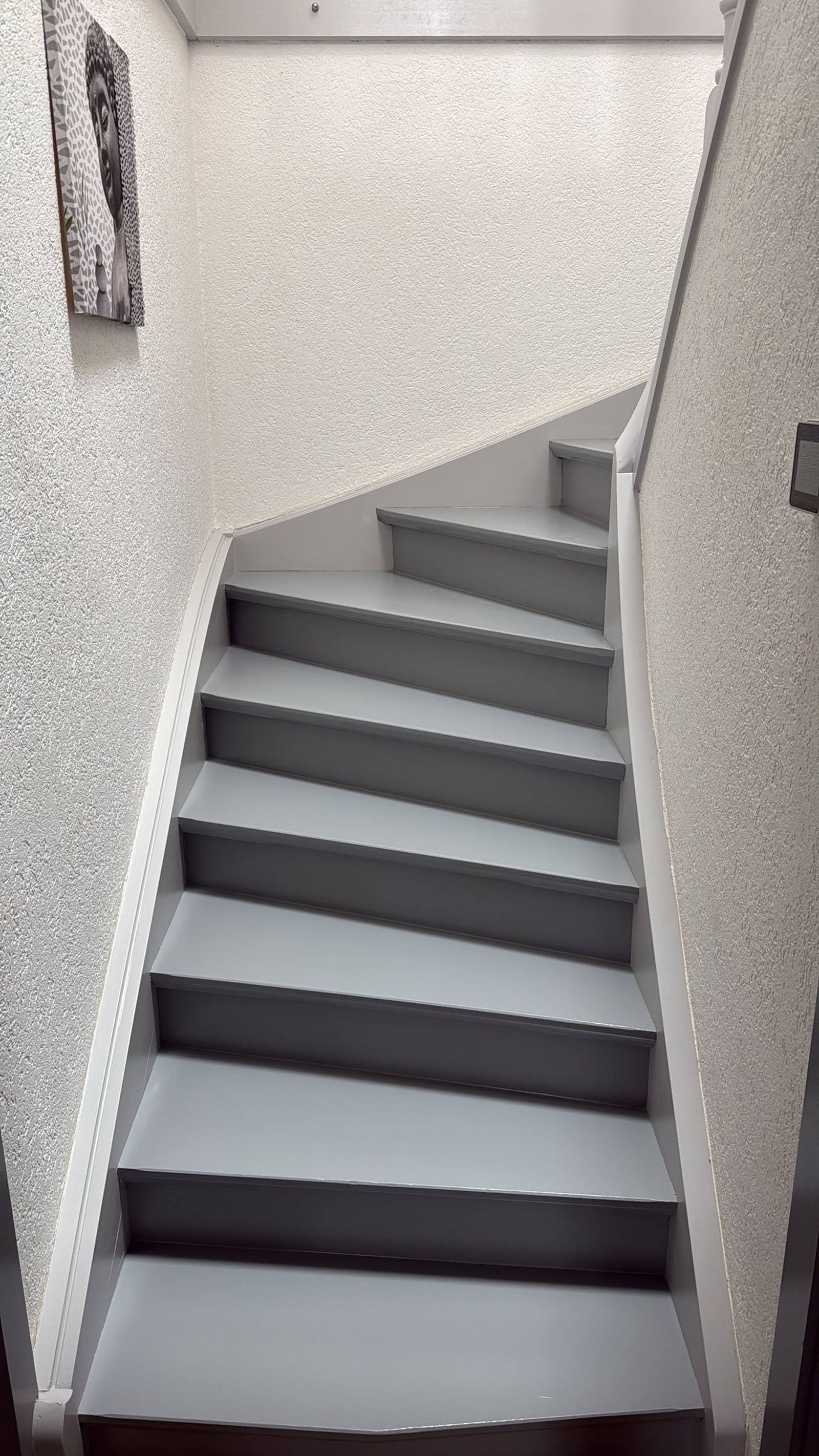 Cage d'escalier rénovée par MNPro — murs gris clair et boiseries blanches
